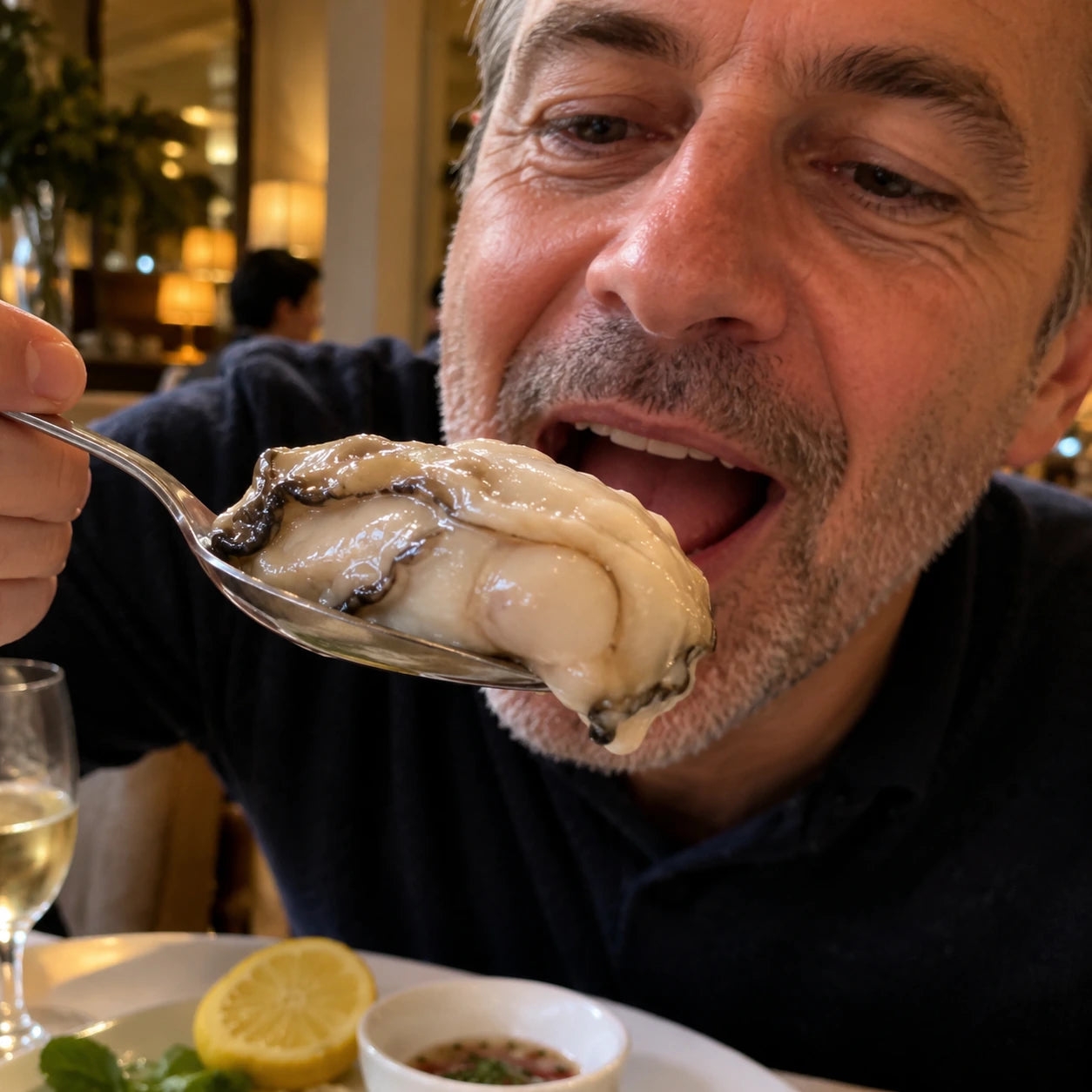 Man holding a spoonful of oyster meat at a restaurant.